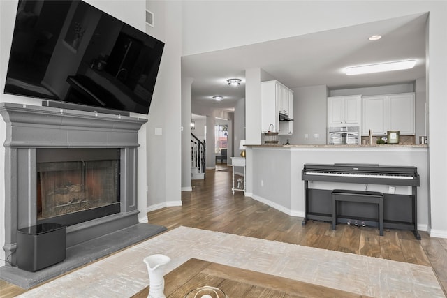 kitchen featuring a fireplace with raised hearth, oven, dark wood-type flooring, visible vents, and white cabinetry