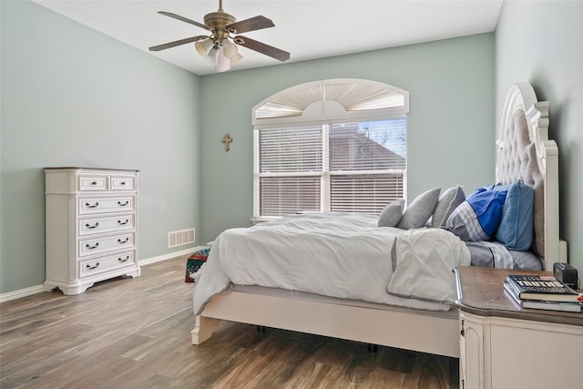 bedroom with a ceiling fan, baseboards, visible vents, and wood finished floors