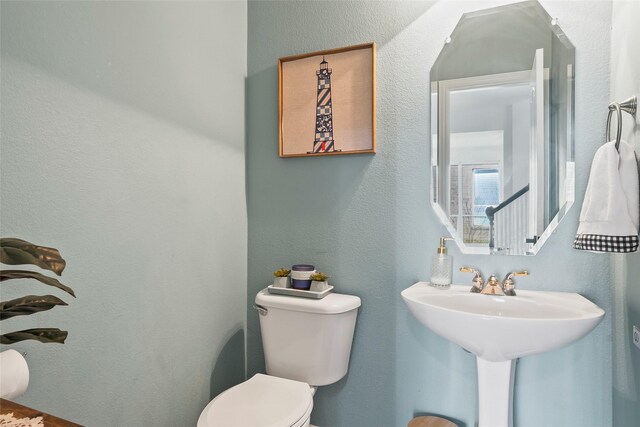 half bath featuring a textured wall and toilet