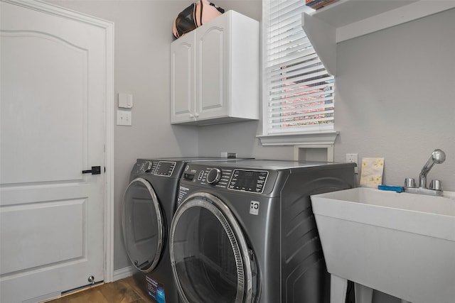 laundry area with dark wood-style floors, cabinet space, a sink, and washing machine and clothes dryer