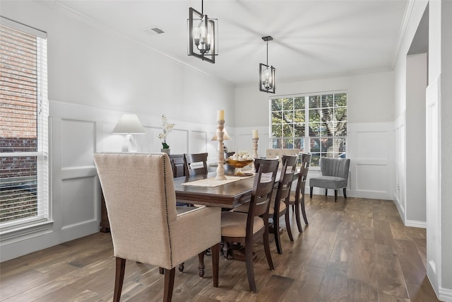 dining space featuring dark wood-style floors, ornamental molding, and an inviting chandelier