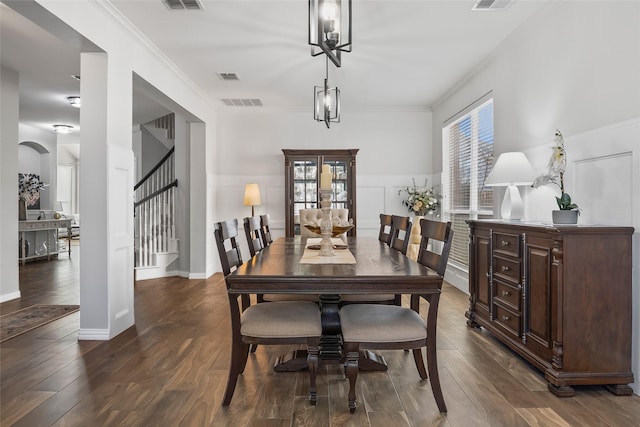 dining space with crown molding, visible vents, dark wood finished floors, and stairway