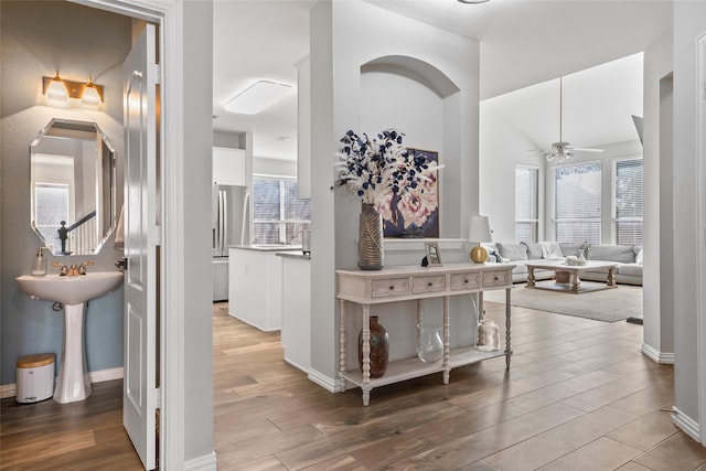 hallway featuring a healthy amount of sunlight, baseboards, and wood finished floors