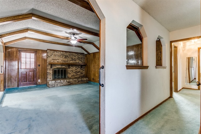 unfurnished living room featuring vaulted ceiling with beams, a textured ceiling, ceiling fan, carpet floors, and a fireplace