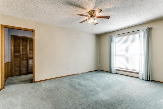 unfurnished room with a textured ceiling, ceiling fan, and light colored carpet