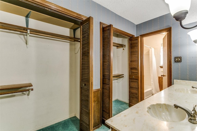 bathroom with a textured ceiling, vanity, and shower / bathtub combination with curtain