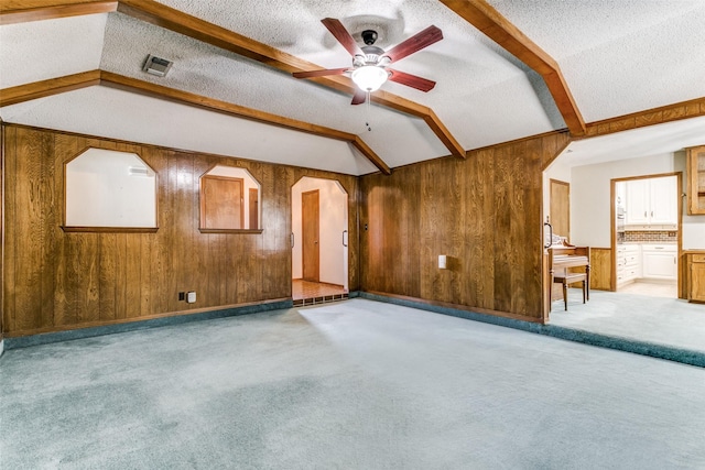 unfurnished room featuring light carpet, vaulted ceiling with beams, wood walls, and a textured ceiling