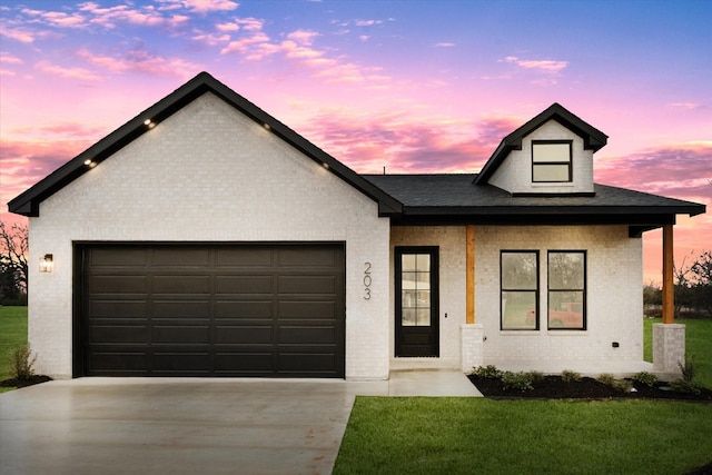 view of front of property with a garage and a lawn