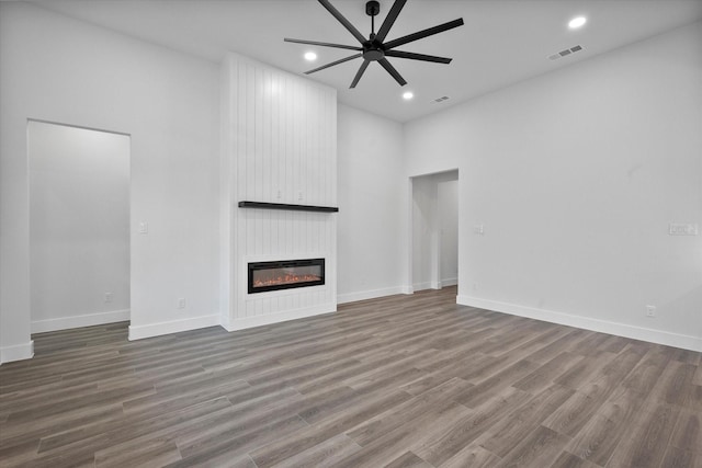 unfurnished living room with ceiling fan, wood-type flooring, and a fireplace