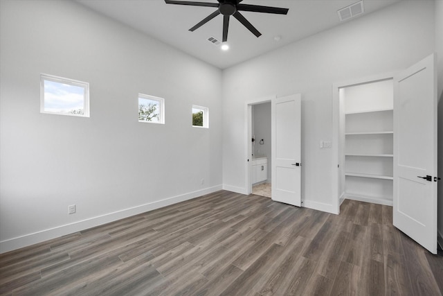 unfurnished bedroom featuring a closet, dark wood-type flooring, ceiling fan, a walk in closet, and ensuite bathroom