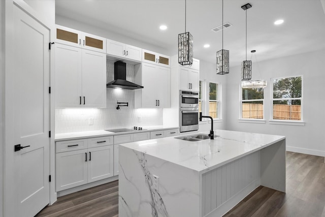 kitchen featuring white cabinets, a center island with sink, wall chimney exhaust hood, and sink