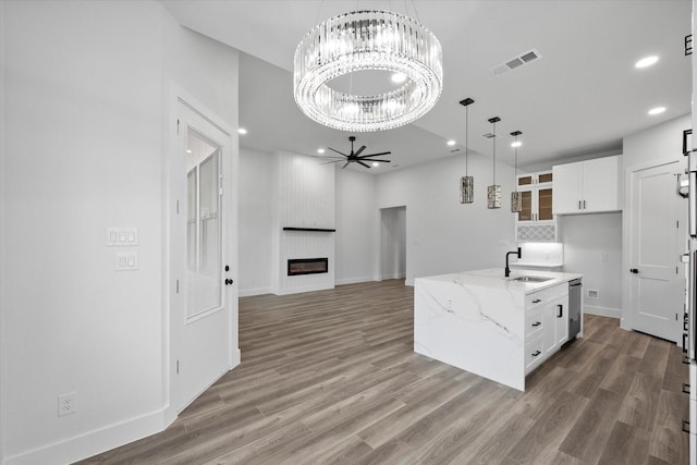 kitchen featuring white cabinetry, sink, light stone countertops, and a fireplace