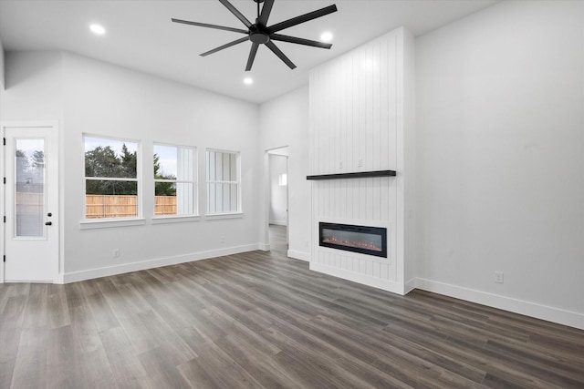 unfurnished living room with ceiling fan, dark wood-type flooring, and a fireplace