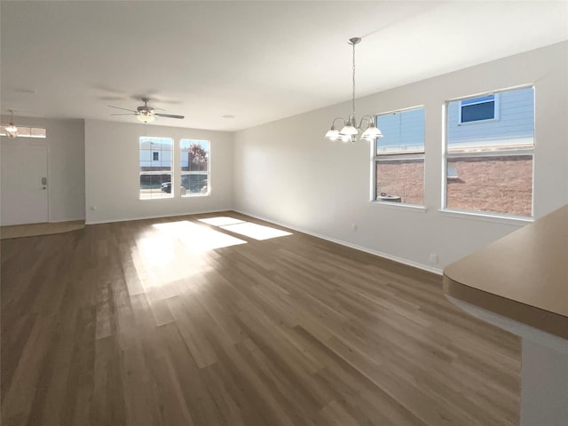 unfurnished living room featuring ceiling fan with notable chandelier and dark hardwood / wood-style flooring