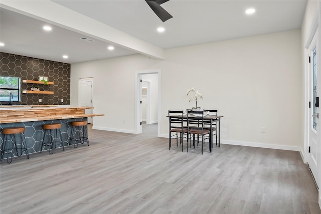 interior space with beam ceiling, light hardwood / wood-style flooring, butcher block counters, and a breakfast bar