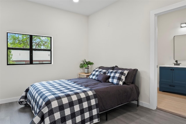 bedroom with sink, ensuite bath, and hardwood / wood-style floors