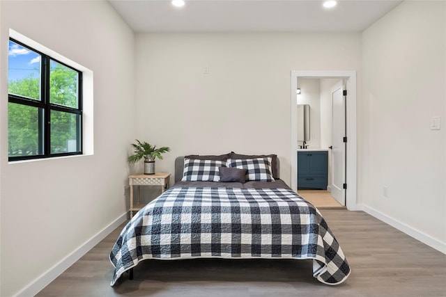 bedroom with light wood-type flooring and ensuite bath