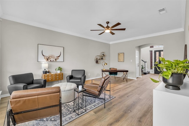 living room with arched walkways, ornamental molding, light wood-type flooring, and visible vents