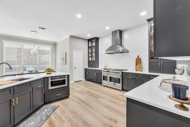 kitchen featuring light countertops, visible vents, glass insert cabinets, wall chimney range hood, and double oven range