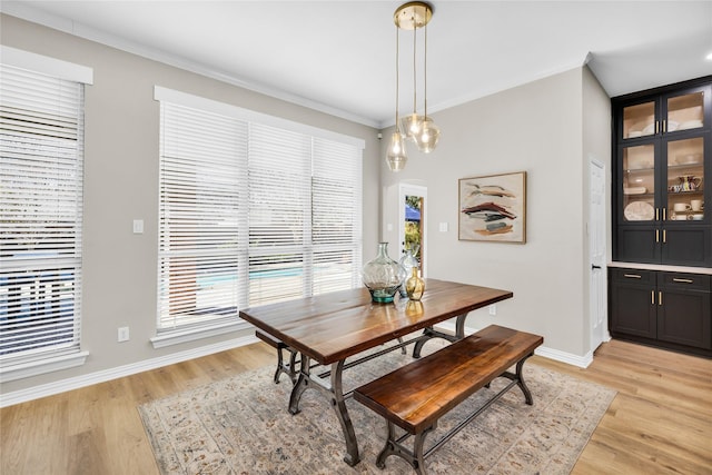 dining area with light wood-style flooring, crown molding, and a wealth of natural light