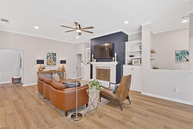 living room with arched walkways, baseboards, a fireplace, and light wood finished floors