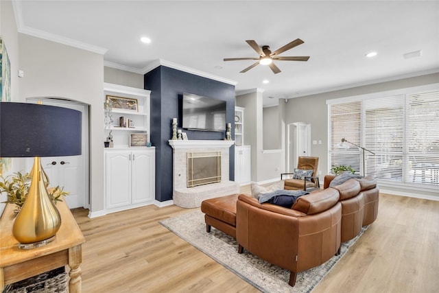 living area featuring ceiling fan, recessed lighting, a fireplace, light wood finished floors, and crown molding