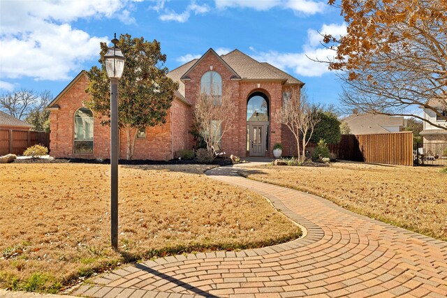 view of front facade featuring brick siding and fence