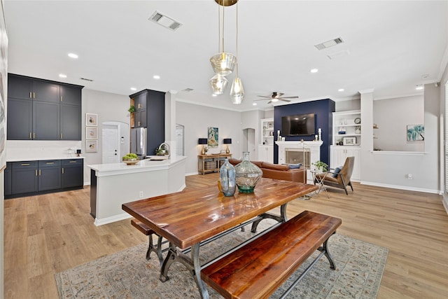 dining room with light wood-style floors, arched walkways, visible vents, and a fireplace