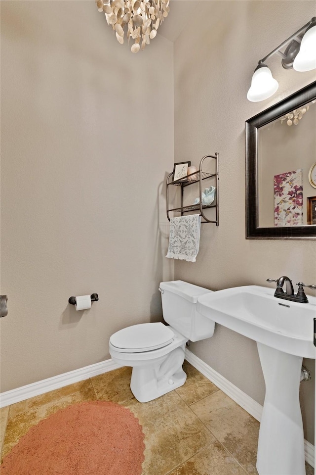 bathroom featuring a notable chandelier, toilet, baseboards, and tile patterned floors