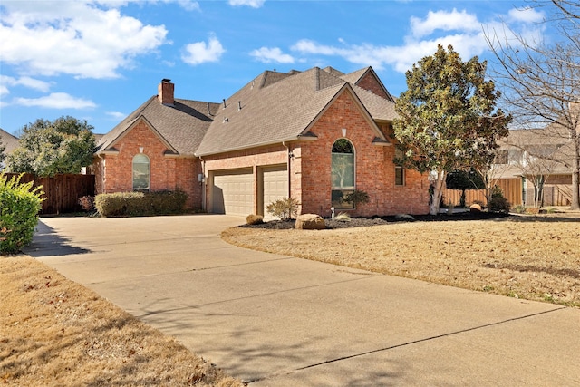 view of front of home featuring brick siding, a shingled roof, fence, concrete driveway, and a chimney