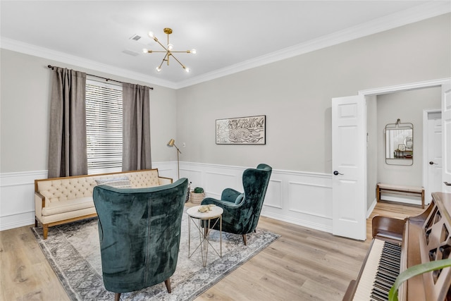 sitting room featuring light wood finished floors, ornamental molding, and a notable chandelier