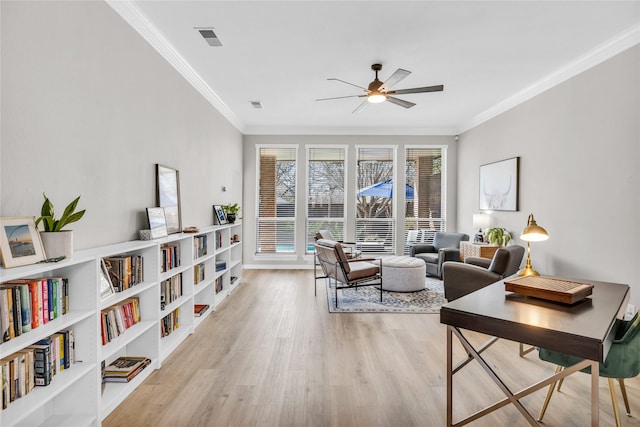 living area featuring ornamental molding, light wood-type flooring, visible vents, and a ceiling fan