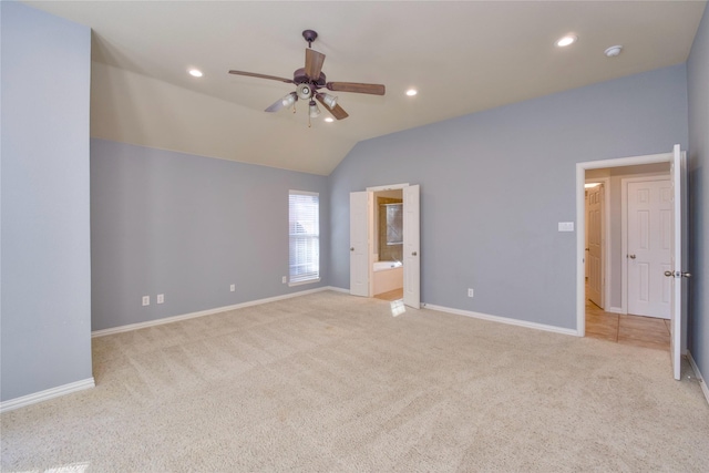 unfurnished bedroom featuring light carpet, ceiling fan, vaulted ceiling, and ensuite bath