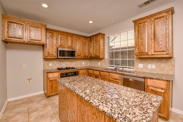 kitchen featuring appliances with stainless steel finishes, light stone countertops, light tile patterned floors, and sink