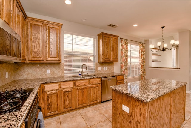 kitchen featuring light stone countertops, black appliances, pendant lighting, a kitchen island, and sink