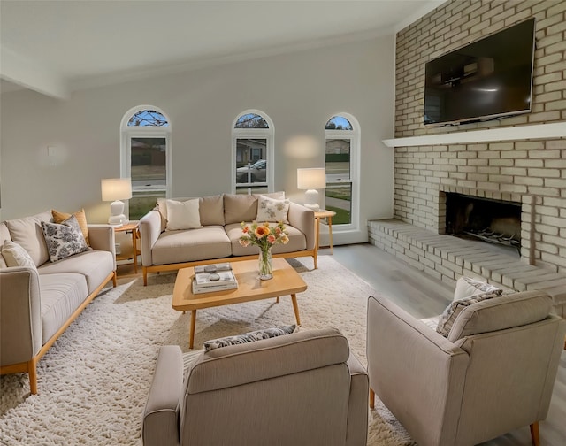 living room with a fireplace, beamed ceiling, crown molding, and light wood-type flooring