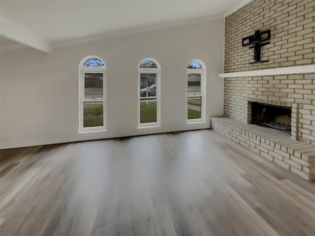 unfurnished living room featuring a fireplace, beam ceiling, crown molding, and hardwood / wood-style flooring