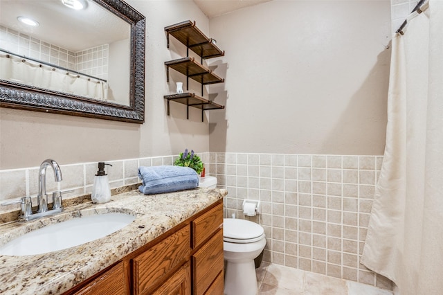 bathroom featuring toilet, tile patterned floors, tile walls, and vanity