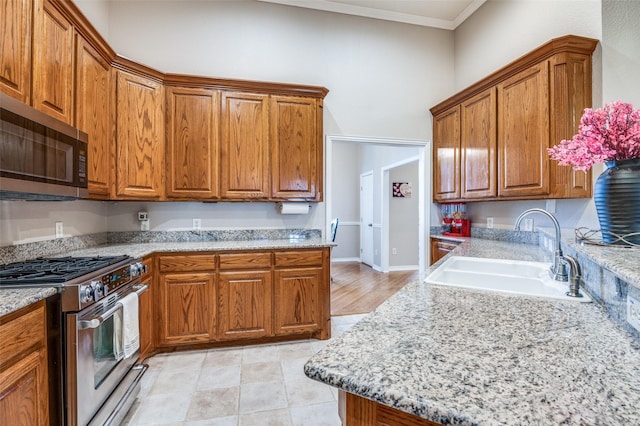 kitchen featuring light tile patterned floors, stainless steel appliances, light stone counters, ornamental molding, and sink