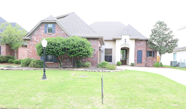 french country style house with cooling unit and a front yard