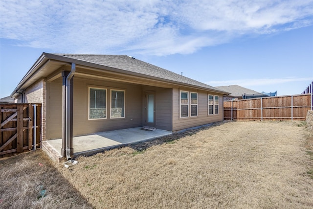 rear view of house with a fenced backyard, a patio, a lawn, and roof with shingles