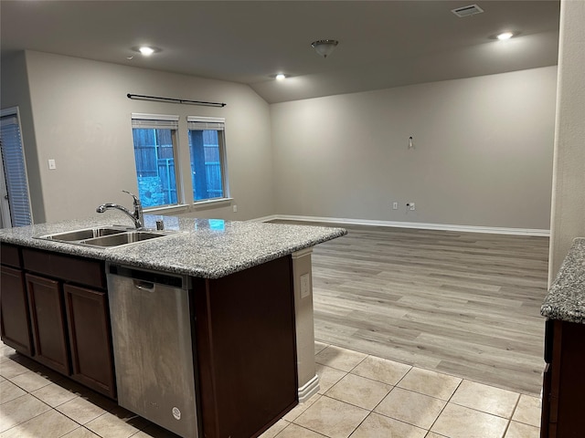 kitchen featuring stainless steel dishwasher, light tile patterned flooring, a sink, and dark brown cabinetry