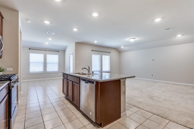 kitchen featuring light tile patterned floors, stainless steel appliances, light carpet, a sink, and an island with sink