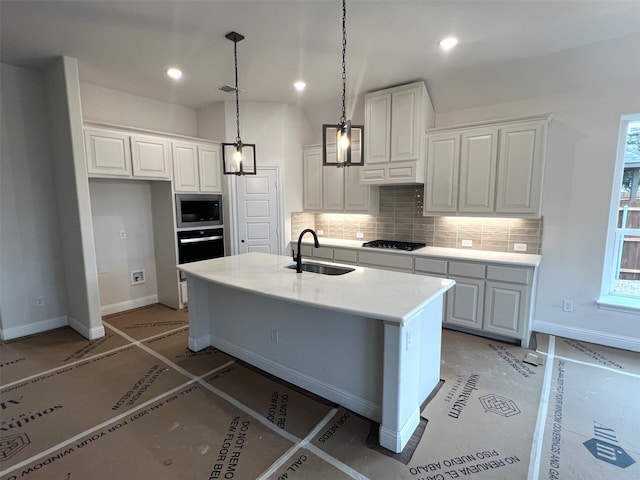 kitchen with an island with sink, decorative light fixtures, sink, white cabinets, and stainless steel microwave