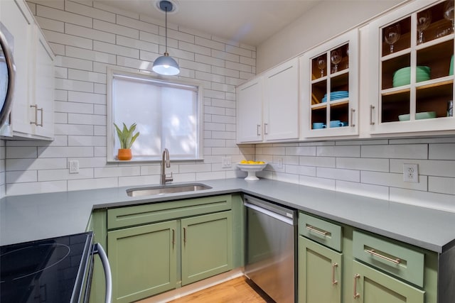 kitchen with tasteful backsplash, hanging light fixtures, stainless steel appliances, white cabinets, and sink