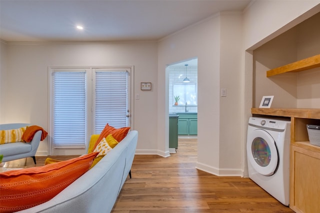 washroom featuring sink, light wood-type flooring, crown molding, and washer / dryer