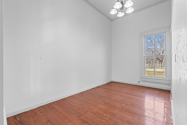 empty room featuring hardwood / wood-style flooring and a chandelier