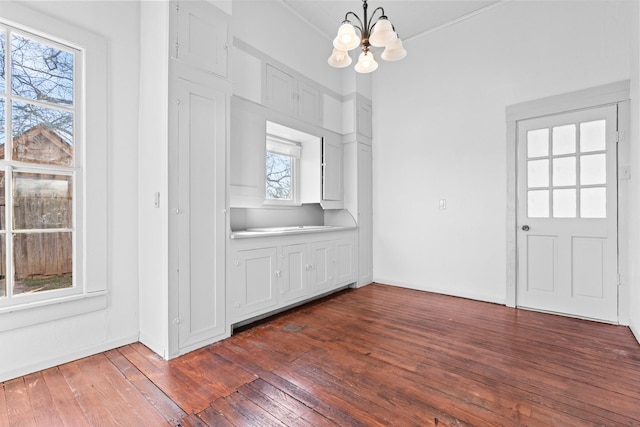 unfurnished dining area with a chandelier and dark hardwood / wood-style floors