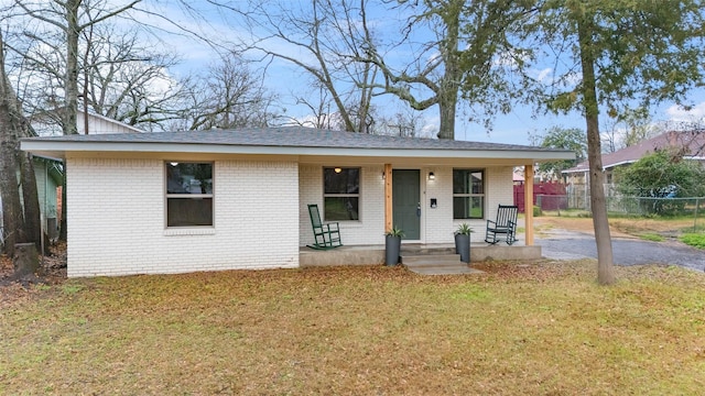 view of front of home featuring brick siding, fence, and a front yard