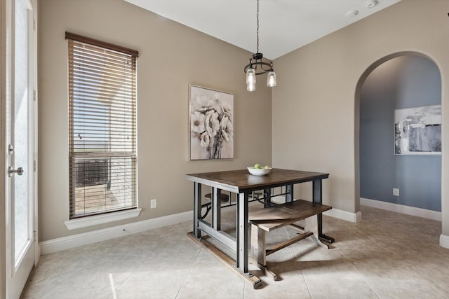 dining room with arched walkways, light tile patterned flooring, and baseboards